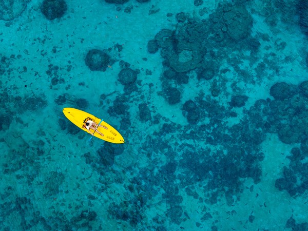 Kayak au‑dessus des coraux dans une eau turquoise.